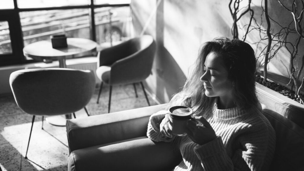 black and white photo of a woman drinking a cup of coffee